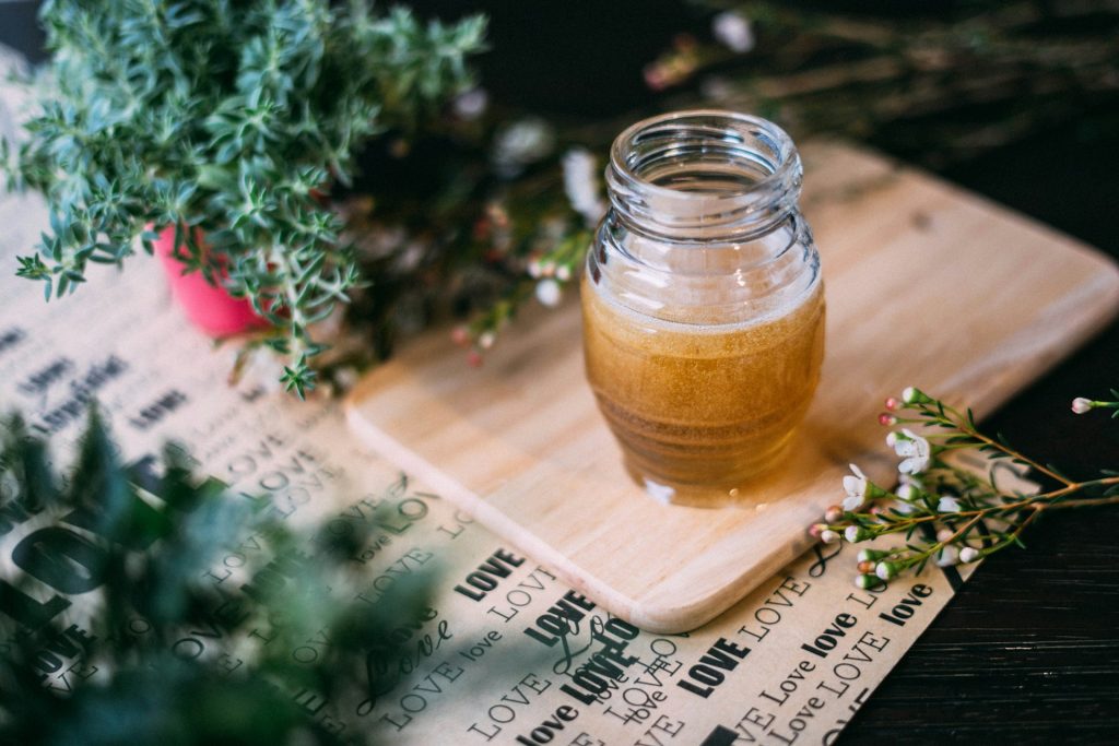 Clear glass jar of honey on a wooden surface photo