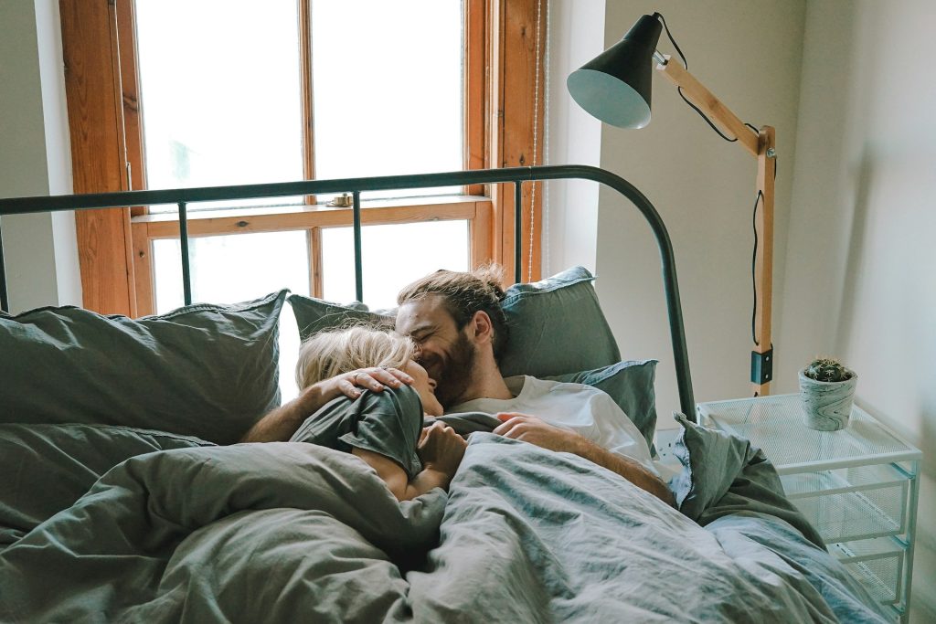 Man kissing woman on her forehead in bed photo